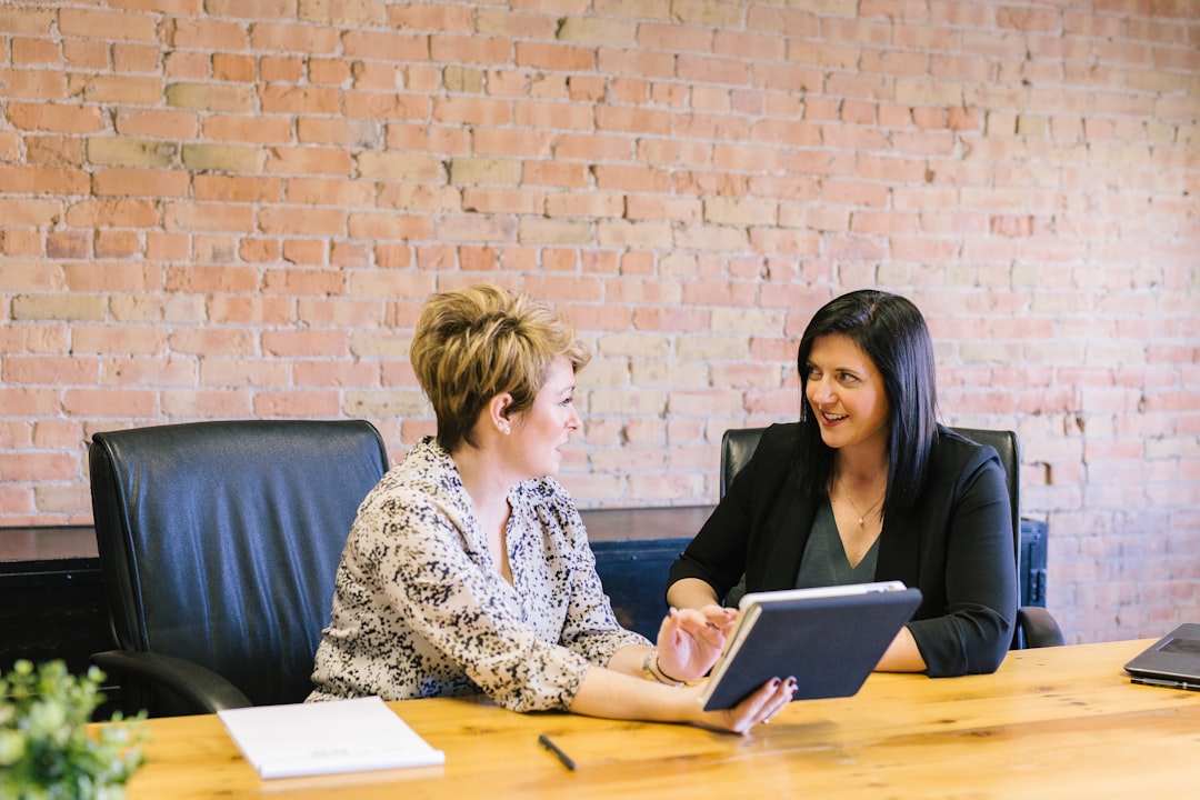 two-women-sitting-on-leather-chairs-in-front-of-table-k0c8ko3e6aa